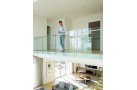 Garde-corps en verre fixation applique à l’anglaise ALX501 sur balcon intérieur, homme debout près de la balustrade vitrée.